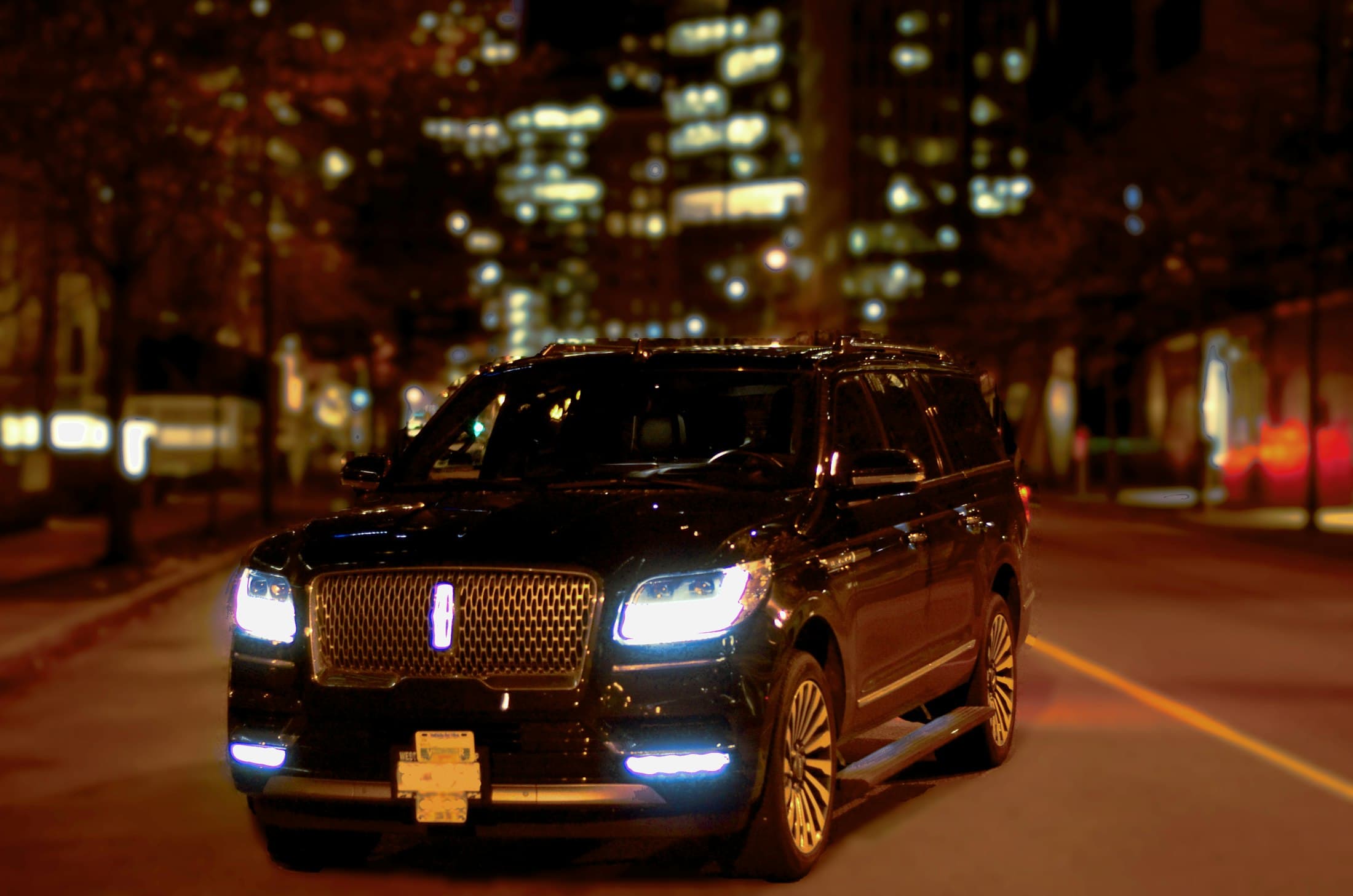 Luxury car headlights glowing on a city street at night
